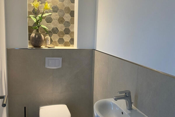 Musterhaus Innenaufnahme Gäste-WC, halbhoch gefliest, mit dekorativer Wandnische
